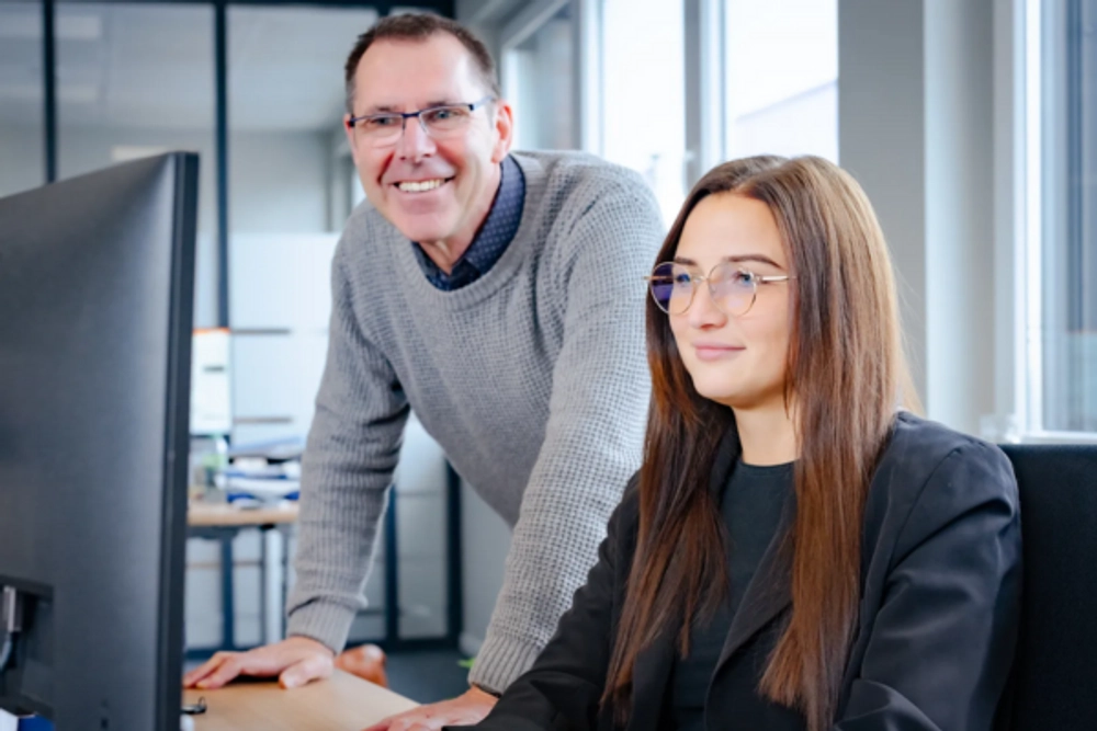 Zwei Mitarbeitende schauen auf einen Monitor